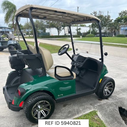 2026 E-Z-GO RXV Freedom Elite golf cart in green with 12-inch wheels, premium seats, Sunbrella enclosure, fan, windshield, mirrors, USB port, LED lights, and Samsung Lithium battery